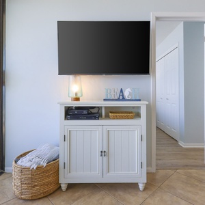 This living area features a stylish TV stand with a beach-themed decor, inviting relaxation and entertainment
