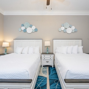 Rest in this inviting guest bedroom featuring two comfortable queen beds and stylish coastal decor