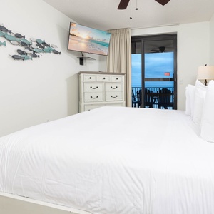 Relax in the master bedroom featuring a large king bed and a beachfront view from the balcony