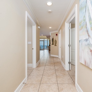 Step into a welcoming hallway adorned with coastal artwork and natural light, leading to stunning views of the beach