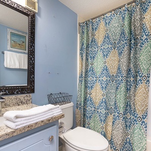 This bathroom features a stylish mirror, colorful shower curtain, and modern amenities for a refreshing experience