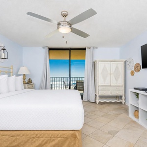 Master bedroom featuring a king bed, coastal decor, and sliding glass doors leading to a balcony with a beach view