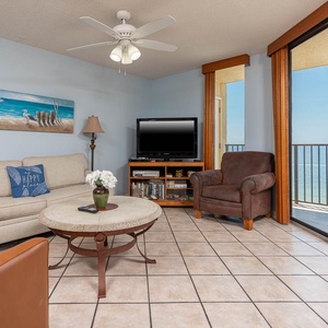 Living area features a light sofa, leather chairs, a coffee table, and a view of the beachfront through large windows