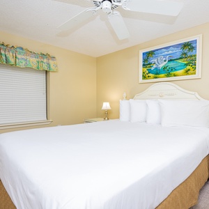 Guest bedroom features a plush queen bed, bedside lamps, and tropical artwork, creating a serene retreat