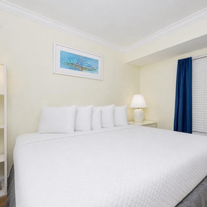King suite with a plush bed, soft lighting, and a charming beach-themed artwork, perfect for relaxation