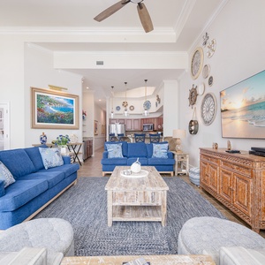Living area featuring blue sofas, coastal decor, and a large TV, perfect for relaxation and entertainment