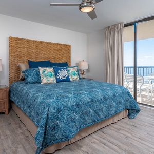 Relax in this serene master bedroom featuring a king bed, coastal decor, and beachfront balcony access