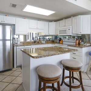 White cabinetry and a spacious island with bar stools create an inviting atmosphere in this stylish kitchen area