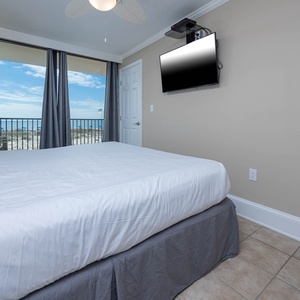 This bedroom features a comfortable bed, a flat-screen TV, and stunning beachfront views through large windows