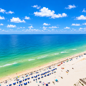 Rows of colorful umbrellas dot the wide beach as you watch children play near the inviting shoreline from above