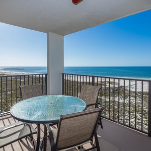 Balcony with a round table and four chairs offers a serene view of the beach and the tranquil gulf waters