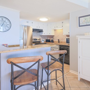 This elegant kitchen features sleek stainless appliances, a breakfast bar with seating, and a light, airy atmosphere