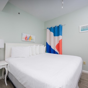 This guest bedroom features a cozy king bed, colorful artwork, and a vibrant curtain, perfect for a restful getaway