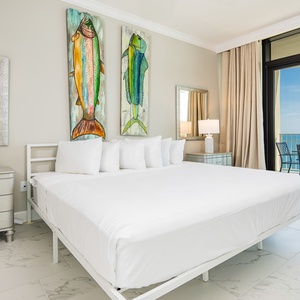 Experience restful nights in the master suite with a king bed, decorative fish art, and beachfront balcony access
