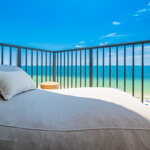 Relax on the cozy lounge chair while enjoying breathtaking views of the turquoise waters and serene beach below