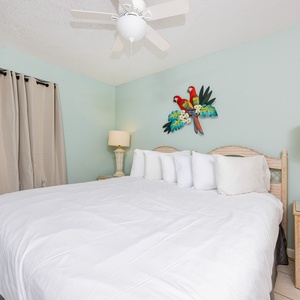 Cheerful guest bedroom featuring a large king bed with multiple pillows, complemented by tropical artwork and soft lighting