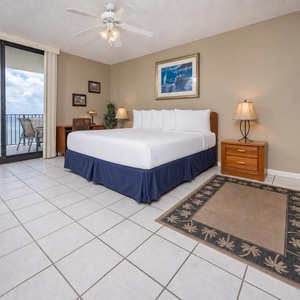 Spacious master bedroom features a king bed, tropical decor, and access to a balcony with views of the beach