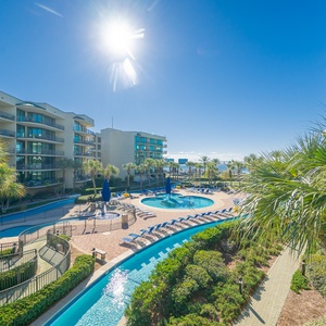 Relax on the balcony, soaking up sunlit views of the inviting pool area and lush surroundings