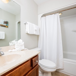 This bathroom features a clean design with a spacious vanity, a shower/tub combo, and fresh towels for your convenience