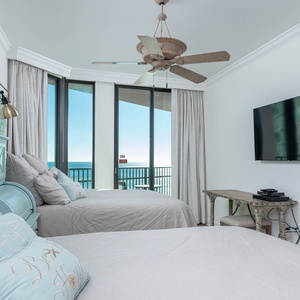 Relax in the serene guest bedroom featuring two queen beds, coastal decor, and large windows with beautiful views