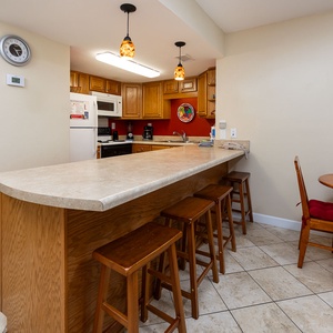 Kitchen featuring wooden cabinets, essential appliances, and a cozy dining area with red accents