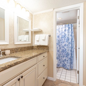 The master bath features a granite countertop, modern fixtures, and a shower with a floral curtain for a refreshing retreat