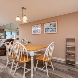 Bright dining area with a wooden table, white chairs, and cozy living room view, perfect for family meals and relaxation