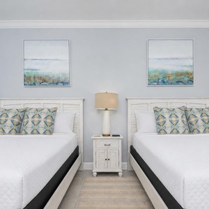 Rest in this inviting guest bedroom featuring two queen beds and calming artwork for a peaceful stay