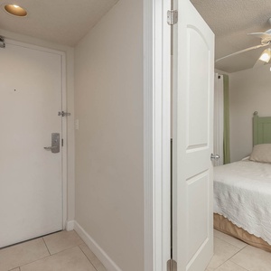 This welcoming entryway shows the guest bedroom with a soft green accent wall and a comfortable queen bed