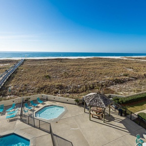 Relax by the pool area with a kiddie pool, surrounded by lush greenery and a pathway leading to the beach just beyond