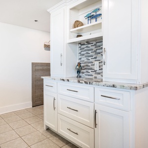 Discover the wet bar area featuring a decorative backsplash and charming coastal accents