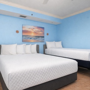 Guest bedroom featuring two comfortable beds, a double and a twin, and cheerful blue walls, perfect for a relaxing getaway