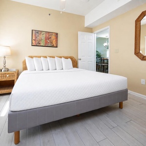 This guest bedroom features a cozy king bed with decorative pillows, a stylish lamp, and a charming mirror