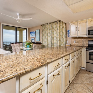 Granite countertop stretches across the kitchen while you prepare fresh meals with coastal views nearby