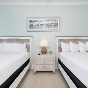 Rest in the tranquil guest room with queens, soft linens, and coastal-inspired decor