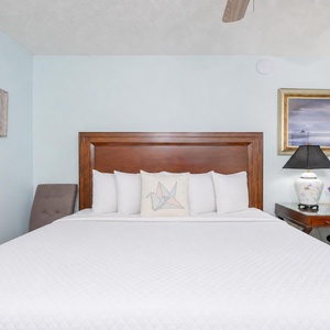 White linens dress the bed in the king suite inviting you to ease into rest after a day on the shore