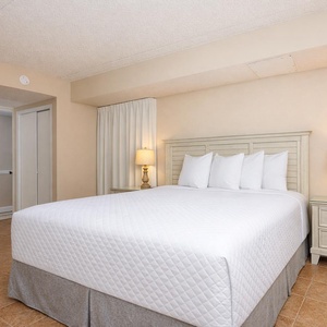 Inviting guest room featuring a queen bed with crisp linens, soft lighting, and easy access to nearby amenities