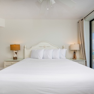 This bedroom features a spacious king bed, soft white linens, and a lovely balcony view for a relaxing getaway