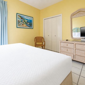 Cozy guest bedroom featuring a comfortable bed, a TV on a wicker dresser, and a charming view