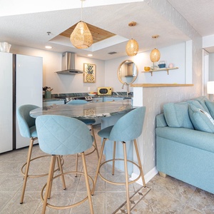 This kitchen features modern smart appliances, a stylish countertops, and a cozy dining area with chic bar stools