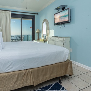 Bright blue walls complement the inviting king bed in the master, while a balcony view showcases the beach