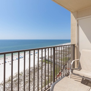 Enjoy a relaxing view from the balcony overlooking the white sand beach and vibrant umbrellas lining the shore