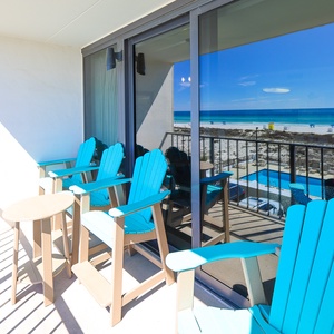 Enjoy a relaxing moment on the balcony with vibrant blue chairs and a stunning beachfront view