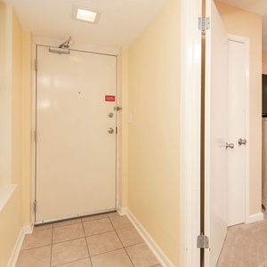 Welcoming entryway features a light-colored wall, tiled floor, and a stylish dresser with seashell accents next to the door