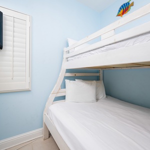 The bunk room features a white bunk bed, a flat-screen TV, and cheerful blue walls, perfect for a fun getaway