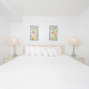Bright and cozy bedroom featuring a king bed, colorful artwork, and elegant lamps for a cozy retreat