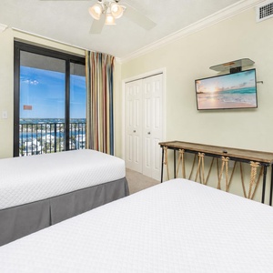 Twin beds in the guest suite offer restful nights and a coastal community view through sliding glass doors
