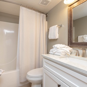 Guest bathroom featuring a tub/shower combo, sleek countertop, and neatly stacked towels for a refreshing experience