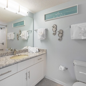 Refresh in this guest bathroom featuring a spacious vanity, decorative accents, and cheerful beach decor