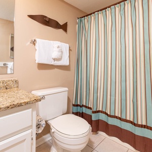 The guest bath features a stylish striped shower curtain, a granite countertop, and fresh towels for your convenience